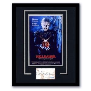 May include: Framed movie poster for the film "Hellraiser." The poster features a central figure with pins in their head, holding a puzzle box. The text reads "Demon to some. Angel to others." and "He'll tear your soul apart."