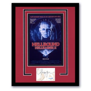 May include: Framed movie poster for "Hellbound: Hellraiser II" with a red mat and black frame. The poster features a blue and white image of a character with pins in their head. The text "Hellbound Hellraiser II" is displayed prominently.