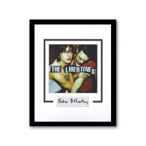 Könnte beinhalten: Ein gerahmtes Schwarzweißfoto von zwei Männern mit dem Text "THE LIBERTINES" in Rot und Weiß gedruckt. Die Unterschrift "Pete Doherty" ist in Schwarz unter dem Bild gedruckt.