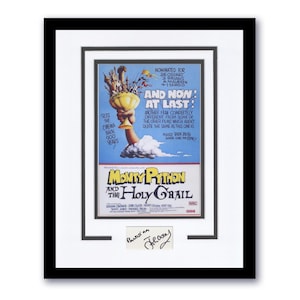 以下が含まれることがあります： 映画「モンティ・パイソン・アンド・ホーリー・グレイル」のポスターが額装されています。青い空を背景に、聖杯を持った手が描かれています。ポスターには、映画監督のテリー・ギリアムのサインが入っています。