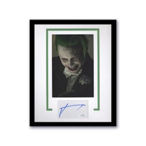 May include: Framed print featuring a portrait of a character with green hair and white face makeup, with the word "Damaged" tattooed on the forehead. The print is in a black frame with a green and white mat, and includes a blue signature.