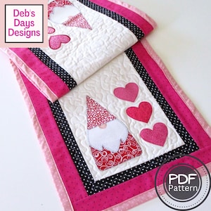 Może przedstawiać: Bieżnik stołowy w kolorze różowym i czarnym z białym tłem przedstawiający gnoma i serca. Tekst "PDF Pattern" znajduje się w kółku w prawym dolnym rogu obrazu.