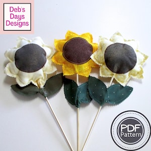 May include: Three handmade fabric sunflowers with dark brown centers, yellow and cream petals, and green leaves. The flowers are attached to wooden dowels. The image includes the text "Deb's Days Designs" and "PDF Pattern".