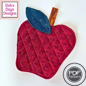 Puede incluir: Posavasos de manzana rojo acolchado con una hoja azul oscuro y un tallo marrón. El posavasos tiene un diseño acolchado y es perfecto para proteger las superficies de los platos calientes.  Patrón PDF.