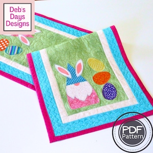Może przedstawiać: Zielony, niebieski, różowy i biały pikowany bieżnik stołowy z gnomem w niebieskim kapeluszu i uszami królika oraz kolorowymi jajkami wielkanocnymi. Tekst "PDF Pattern" znajduje się na białym kole z czarnym obramowaniem.