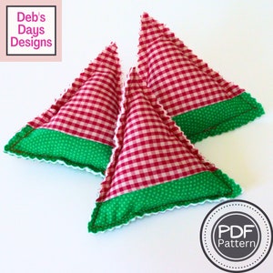 May include: Three red and white gingham fabric triangle pillows with green polka dot fabric trim. The pillows are sewn with a white zig-zag stitch. The text "PDF Pattern" is in a circle on the bottom right of the image.
