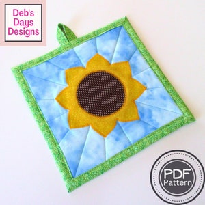 Könnte beinhalten: Ein gesteppter Sonnenblumen-Topflappen mit grünem Rand und blauem Hintergrund. Die Sonnenblume hat eine braune Mitte und gelbe Blütenblätter. Der Text "PDF Pattern" befindet sich auf einem weißen Kreis mit grauem Rand.