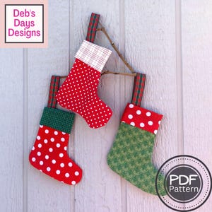 Może przedstawiać: Trzy czerwono-zielone świąteczne skarpety w białe kropki wiszące na gałęzi. Skarpety są wykonane z tkaniny i mają różne wzory. Tekst "PDF Pattern" jest widoczny w prawym dolnym rogu obrazu.
