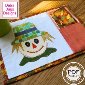 May include: A quilted fabric coaster with a scarecrow face and a pocket for a tea bag. The coaster has a brown, orange, and yellow floral border. The text "PDF Pattern" is visible in the lower right corner of the image.