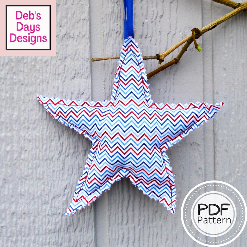 May include: A red, white, and blue chevron patterned fabric star with a frayed edge. The star is hanging from a blue ribbon and is against a white wood background. The text "PDF Pattern" is in a circle on the bottom right of the image.