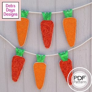 May include: A string of six carrot-shaped fabric decorations, each with a green top, hanging from a white string against a light gray wood background. The carrots are made of different fabrics, some with a swirl pattern and others with a speckled pattern. The text "PDF Pattern" is visible in a circle at the bottom right of the image.