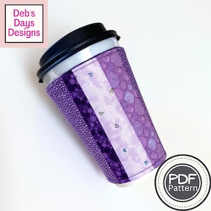 May include: Purple and white fabric coffee cup cozy with a heart pattern. The cozy is made of multiple fabric strips sewn together. The text "PDF Pattern" is visible in the lower right corner of the image.