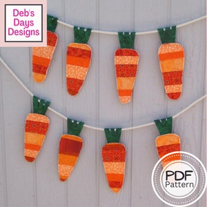 May include: A string of eight orange and green felt carrot decorations hanging on a white wall. The carrots are made of patchwork fabric with different patterns. The text "PDF Pattern" is visible in the lower right corner of the image.