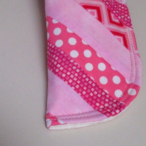 Puede incluir: Tela rosa y blanca con un patr&oacute;n de rayas diagonales. La tela est&aacute; cosida para crear una forma curva.