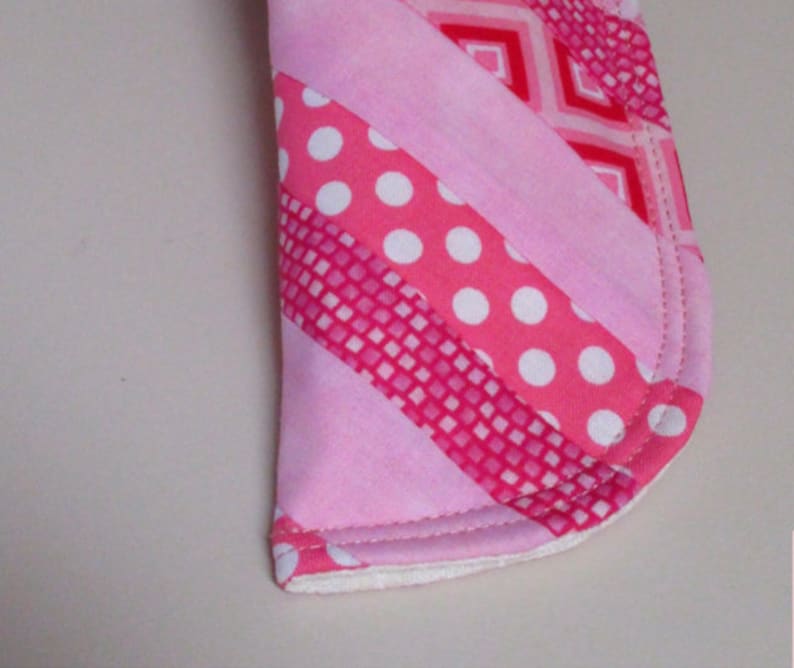 Puede incluir: Tela rosa y blanca con un patr&oacute;n de rayas diagonales. La tela est&aacute; cosida para crear una forma curva.