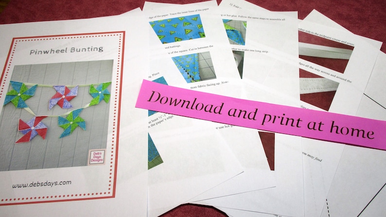 May include: A collection of printed instructions and a sample image for making pinwheel bunting. The sample image shows a garland of colorful pinwheels in red, blue, and green. The text "Download and print at home" is visible on a pink strip.