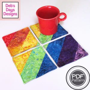 May include: A red ceramic mug sits on four colorful fabric coasters. Each coaster features a diagonal pattern in shades of red, yellow, green, blue, and purple. The coasters are square with black edging. The image includes the text "Deb's Days Designs" and "PDF Pattern".