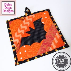 May include: A Halloween-themed quilted hot pad with a black bat design. The hot pad is made with orange, black, and white fabric and has a candy corn trim. The text "PDF Pattern" is visible in the lower right corner of the image.