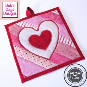 May include: A red and pink quilted pot holder with a white heart and a red heart inside. The pot holder has a loop for hanging. The text "PDF Pattern" is on a white circle with a black border.