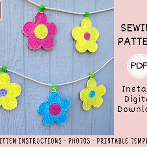 May include: A sewing pattern for a flower garland. The pattern includes written instructions, photos, and a printable template. The garland is made of five flowers in pink, yellow, and blue.