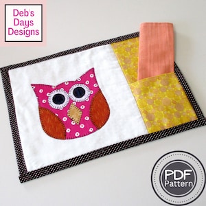 May include: A pink owl with white polka dots and brown accents is appliqued on a white fabric placemat with a black and white polka dot border. A yellow fabric pocket with a swirl pattern is on the right side of the placemat. A peach colored napkin is in the pocket. The text "PDF Pattern" is on a white circle with a gray border.