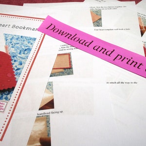 May include: A pink paper strip with the text "Download and print at home" on it. The paper strip is on top of a white sheet of paper with instructions for making a corner heart bookmark. The instructions include a diagram of a heart shape and the text "Corner Heart Bookmark".