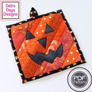 May include: A quilted pumpkin-shaped hot pad with a black face and a candy corn border. The text "PDF Pattern" is on a white circle in the lower right corner of the image.