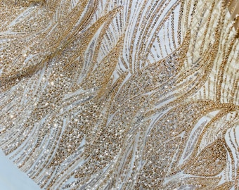 May include: A sheer fabric featuring an intricate pattern of gold and silver sequins arranged in flowing, wave-like lines. The design incorporates dense beadwork and metallic embroidery that creates a shimmering, textured surface across the material.
