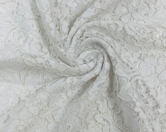 May include: White lace fabric with a delicate floral pattern. The fabric is soft and sheer, and it has a slightly textured surface.