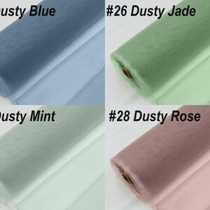 May include: Four rolls of tulle fabric in different colours: dusty blue, dusty jade, dusty mint, and dusty rose. The fabric is rolled up and the ends are visible.