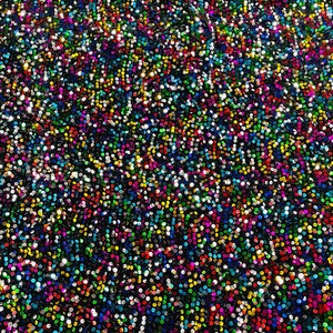 May include: A close-up of a fabric covered in iridescent sequins. The sequins are a variety of colors, including silver, gold, red, blue, green, and purple.