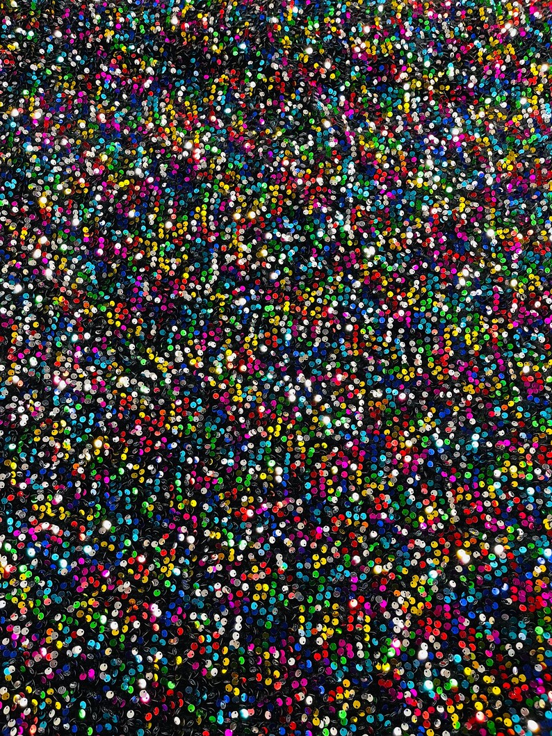 May include: A close-up of a fabric covered in iridescent sequins. The sequins are a variety of colors, including silver, gold, red, blue, green, and purple.