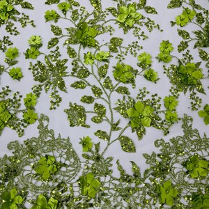 May include: Green floral lace fabric with 3D flowers and sequins. The fabric has a delicate, intricate design and is perfect for adding a touch of elegance to any project.