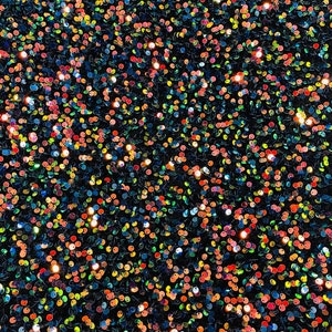 May include: A close-up of a fabric covered in iridescent sequins. The sequins are a mix of blue, green, orange, and pink.