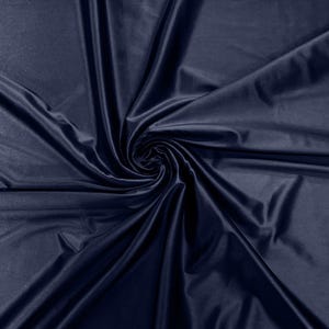 May include: A close-up of a deep blue fabric with a smooth, silky texture. The fabric is draped and folded, creating a swirling pattern.
