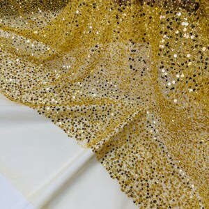 May include: Gold sequin fabric with a mesh backing. The sequins are small and densely packed, creating a shimmering effect.