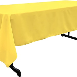 May include: A bright yellow rectangular tablecloth draped over a table. The tablecloth has a smooth, wrinkle-free surface.