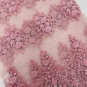 May include: Pink beaded lace fabric with floral designs. The fabric has a delicate, sheer texture and is adorned with intricate beading and sequins.