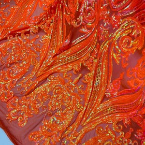 May include: Orange iridescent sequins on a sheer mesh fabric. The sequins are arranged in a floral pattern.