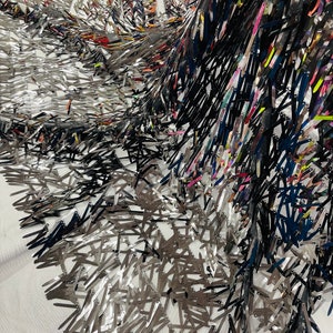 May include: Black and silver sequined fabric with a fringe design. The sequins are arranged in a random pattern and create a shimmering effect.