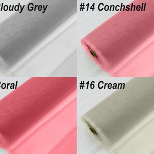 May include: Four rolls of tulle fabric in different colours: cloudy grey, conchshell, coral, and cream. The fabric is rolled up and the ends are visible.