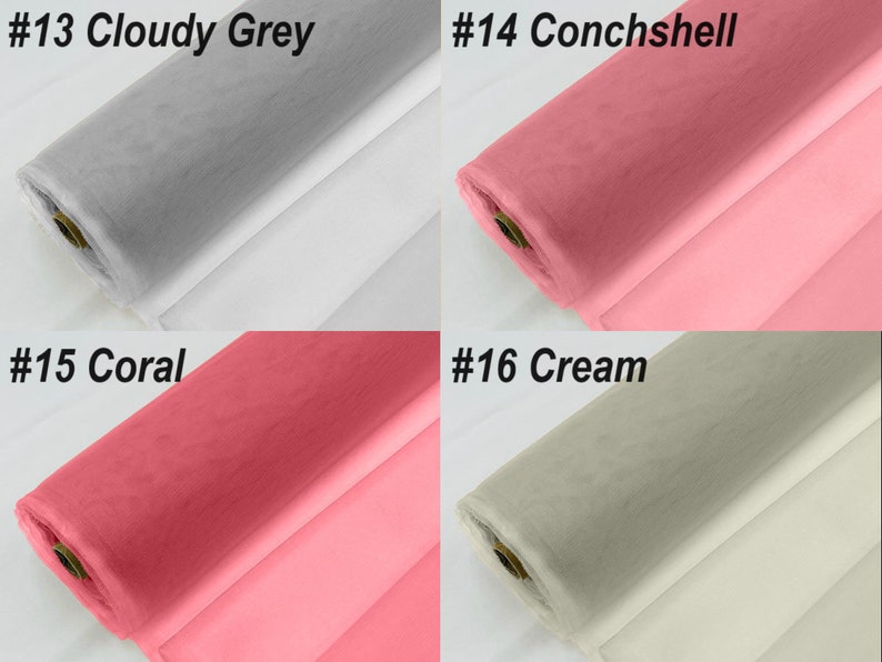 May include: Four rolls of tulle fabric in different colours: cloudy grey, conchshell, coral, and cream. The fabric is rolled up and the ends are visible.