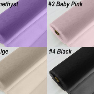 May include: Four rolls of tulle fabric in different colours: amethyst, baby pink, beige, and black. The fabric is rolled up and the ends are visible.