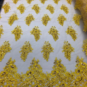 May include: Yellow floral lace fabric with a delicate pattern and gold accents. The lace is on a white mesh background.