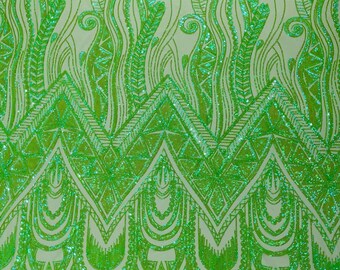 May include: Green sequined fabric with a geometric pattern. The pattern features a series of cascading teardrop shapes and a repeating chevron design.