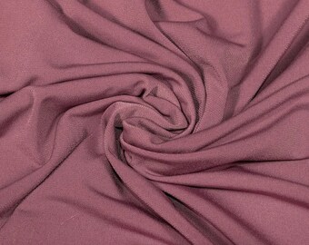 May include: A close-up of a soft, mauve-colored fabric with a smooth, slightly textured surface. The fabric is draped and folded, creating a sense of movement and flow.