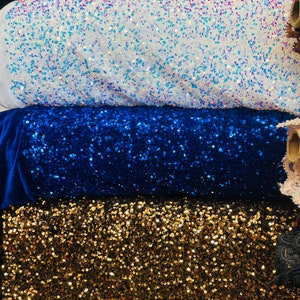 May include: Four rolls of sequined fabric in different colors: red, white, blue, and gold. The fabric is made of small, round sequins that are sewn onto a mesh backing.