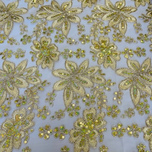 Könnte beinhalten: Goldene Blumenspitze mit Pailletten. Die Spitze hat ein zartes Blumenmuster mit kleinen Pailletten. Der Stoff ist leicht und durchsichtig.