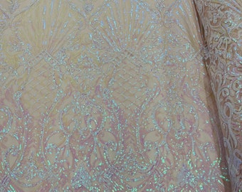 Op de afbeelding: Iridescent roze en witte paillettenstof met een bloemenpatroon. De pailletten zijn gerangschikt in een herhalend patroon van swirls en bladeren.