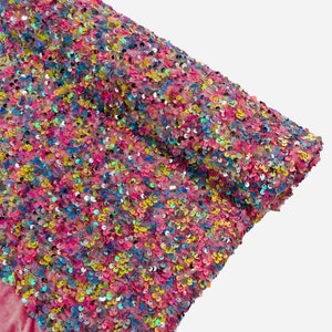 May include: Pink velvet fabric with iridescent sequins in a variety of colors, including pink, blue, green, and yellow.